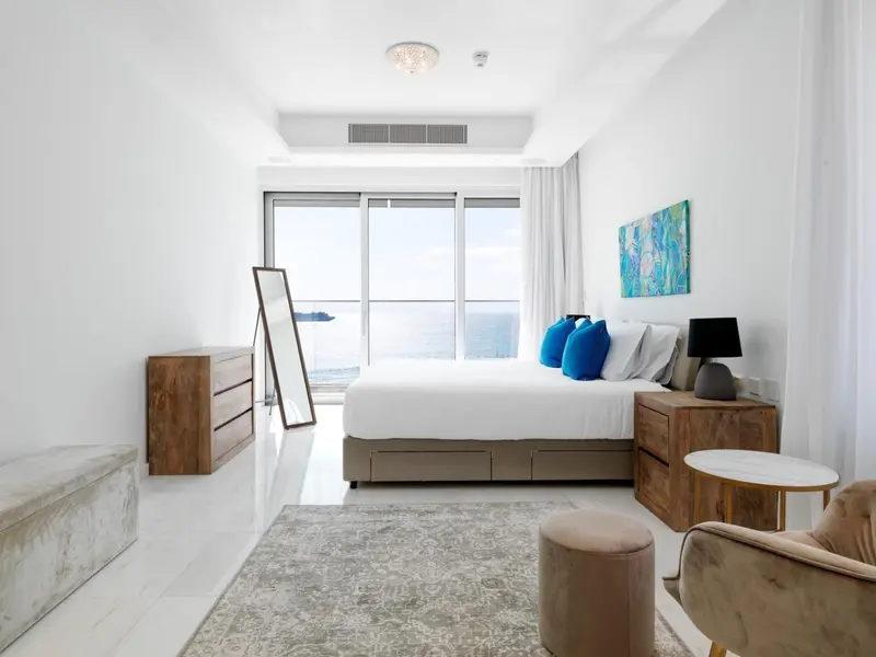Chambre lumineuse avec un grand lit et une vue sur la mer.