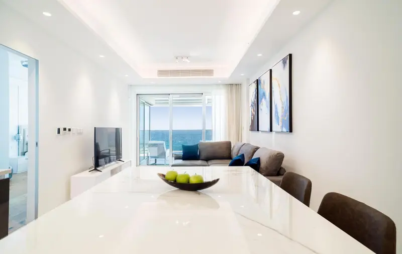 Un salon lumineux avec un coin repas et une vue sur la mer.