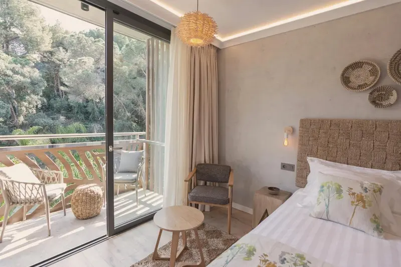 Une chambre lumineuse s'ouvre sur une terrasse avec mobilier d'extérieur.