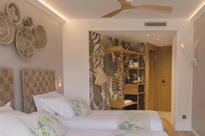 Une chambre lumineuse avec un lit double et une décoration murale tropicale.