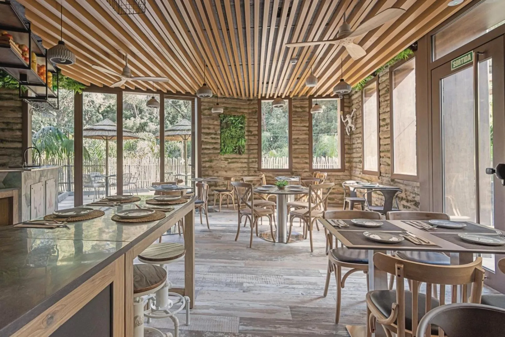 Une salle à manger lumineuse avec des tables dressées et un plafond en bois.