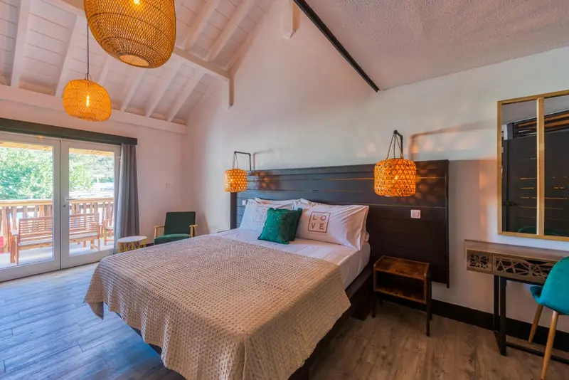 Une chambre lumineuse avec un grand lit et une décoration en rotin.