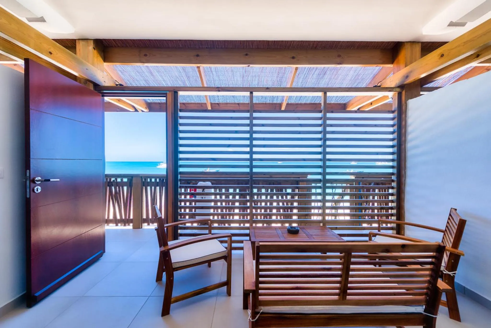 Terrasse aménagée avec mobilier en bois et vue sur la mer.