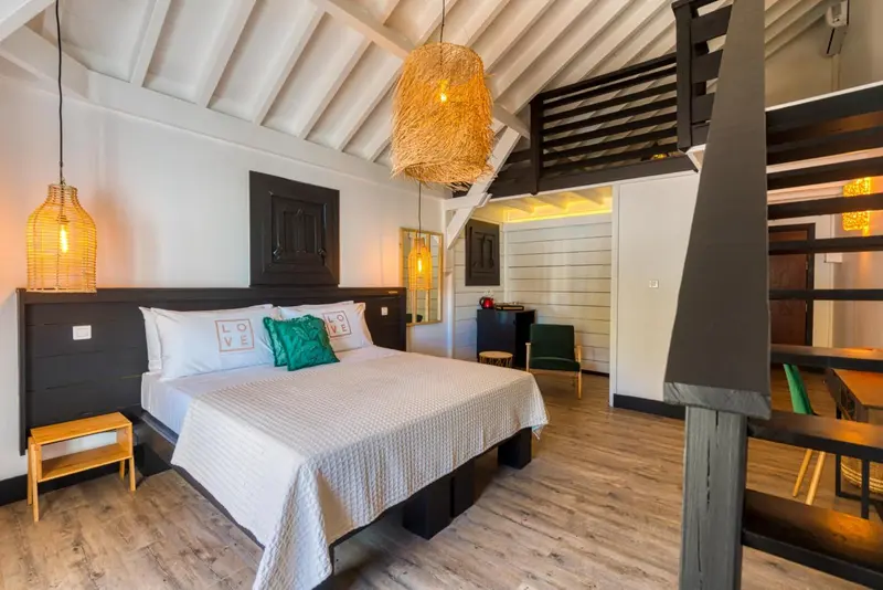 Une chambre lumineuse avec un grand lit recouvert de linge blanc.