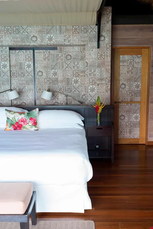 Lit blanc avec oreillers colorés dans une chambre décorée de motifs géométriques.