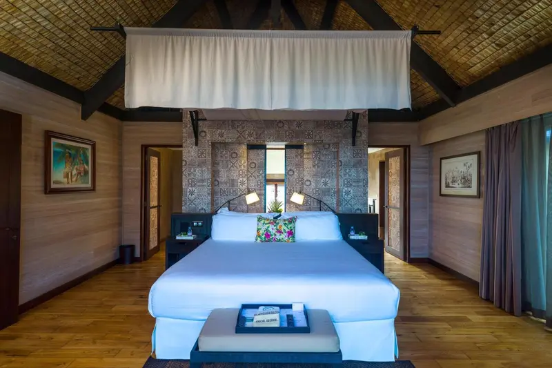 Une chambre lumineuse avec un grand lit recouvert de blanc.