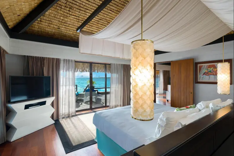 Une chambre lumineuse avec un lit à baldaquin donnant sur l'océan.