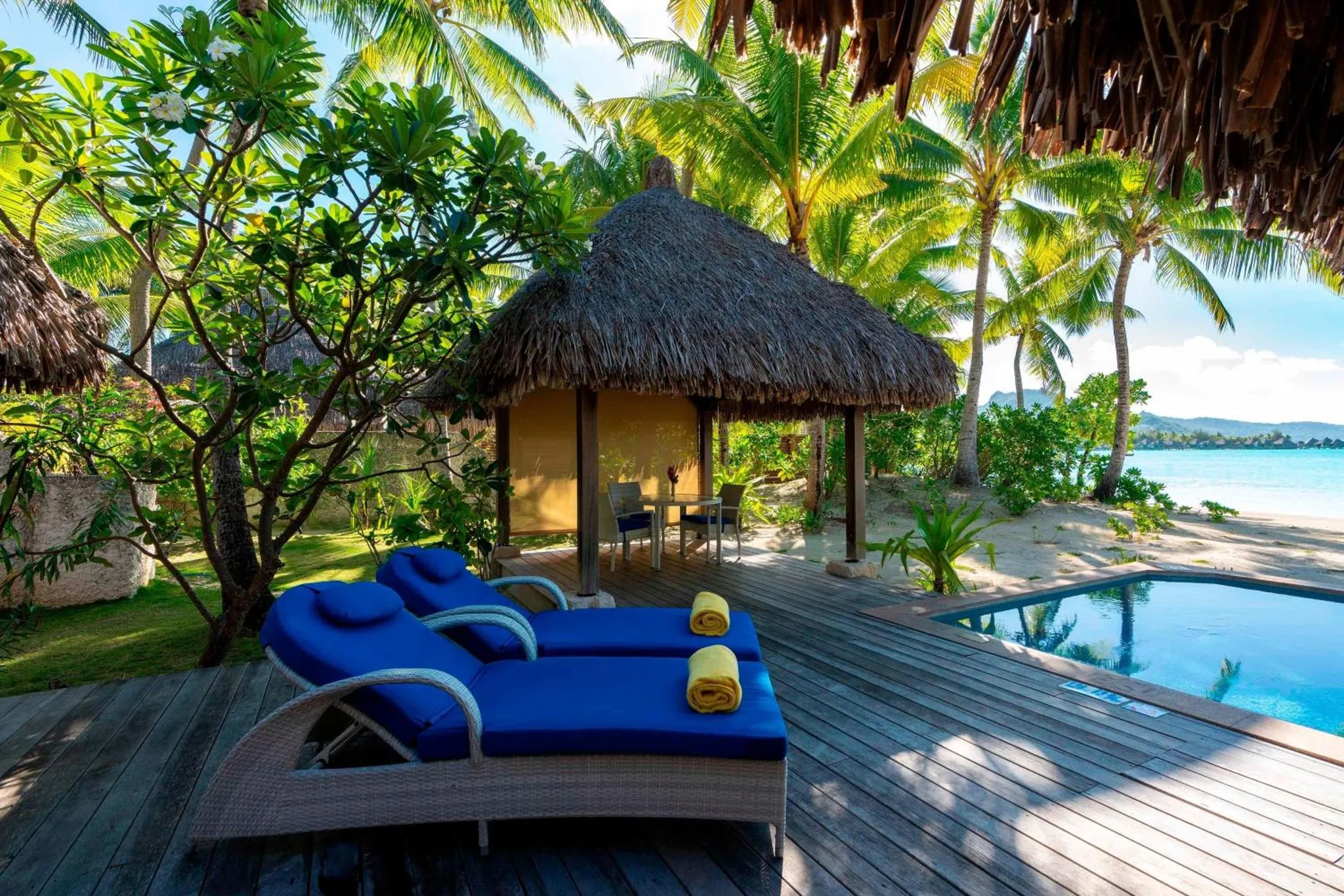 Terrasse en bois avec chaises longues et piscine face à la mer.