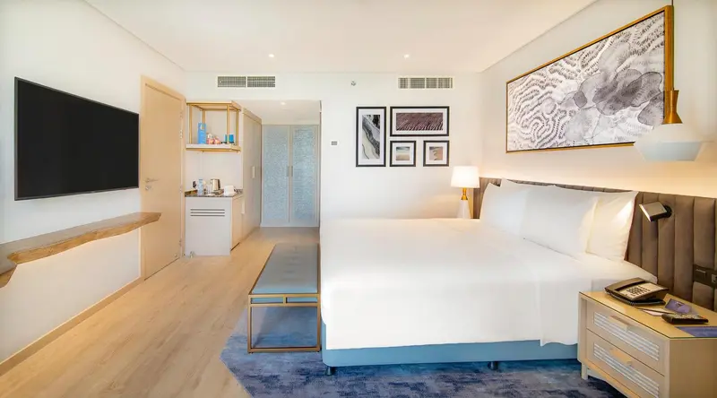 Une chambre lumineuse avec un grand lit et une télévision murale.