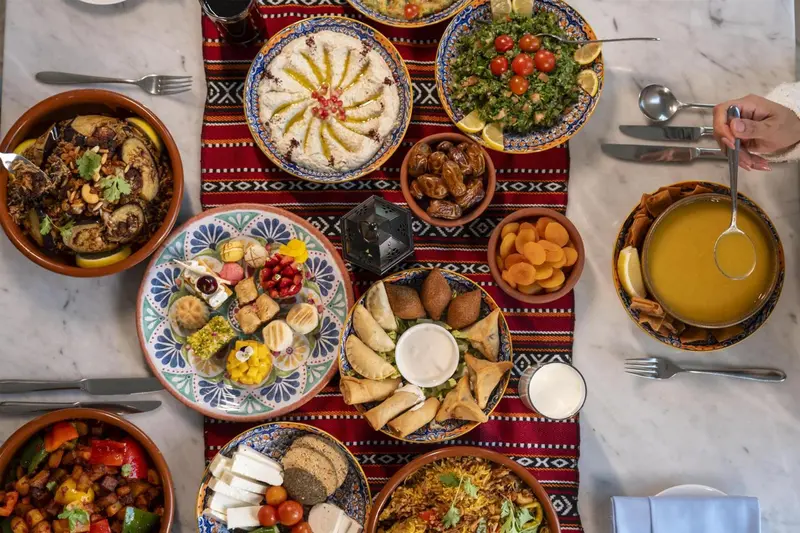 Une table vue d'en haut est dressée de nombreux plats colorés et variés.