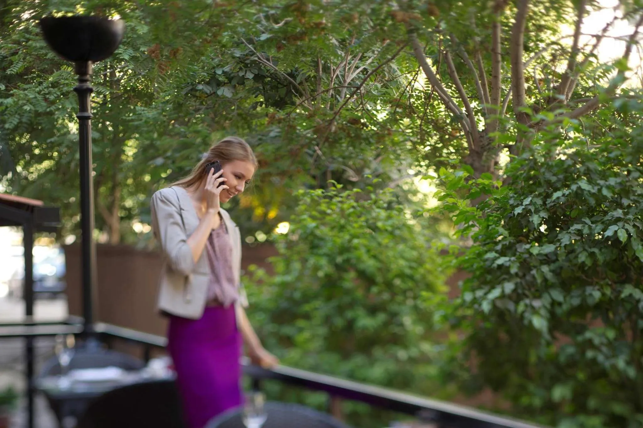 Une femme souriante parle au téléphone sur une terrasse.
