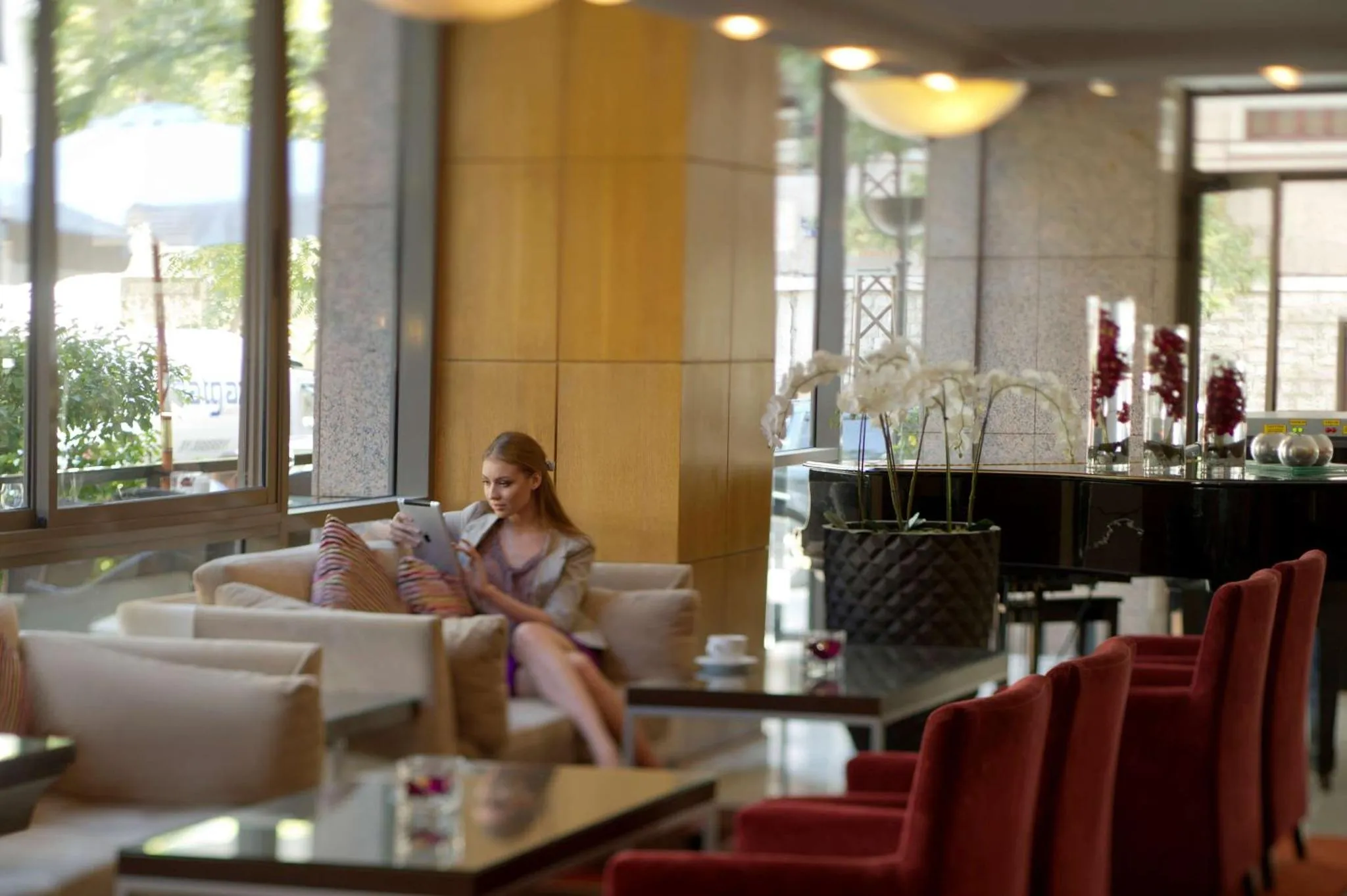 Une femme est assise sur un canapé dans un espace de détente avec des fauteuils et des tables basses.