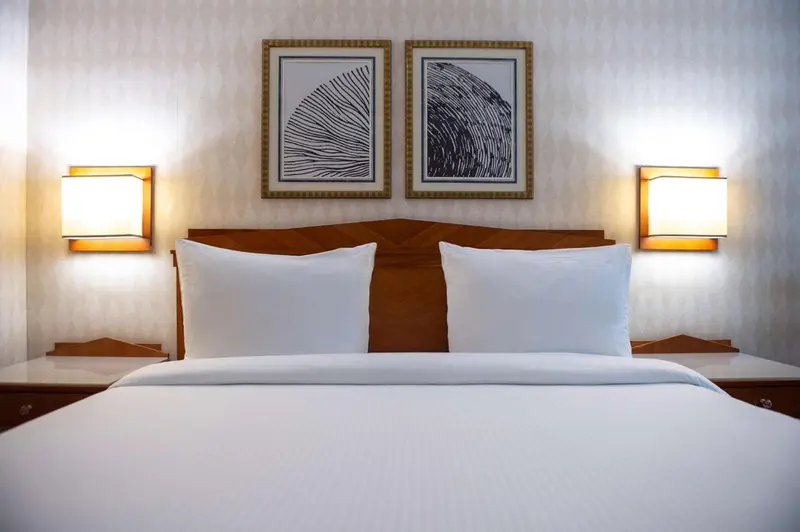 Un lit double blanc est dispose dans une chambre d'hotel.
