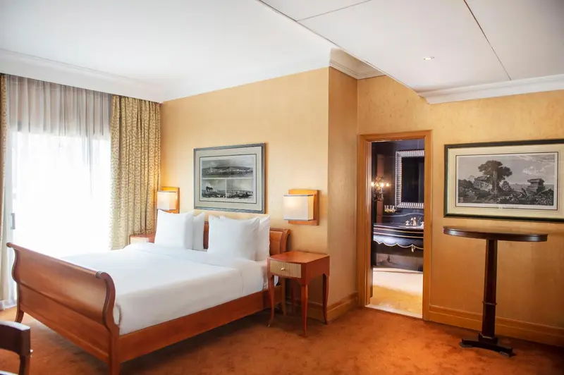 Une chambre lumineuse avec un grand lit et des tableaux décoratifs.