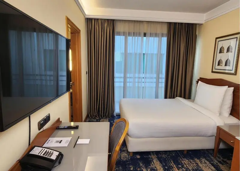 Une chambre d'hôtel lumineuse avec un lit et un bureau.