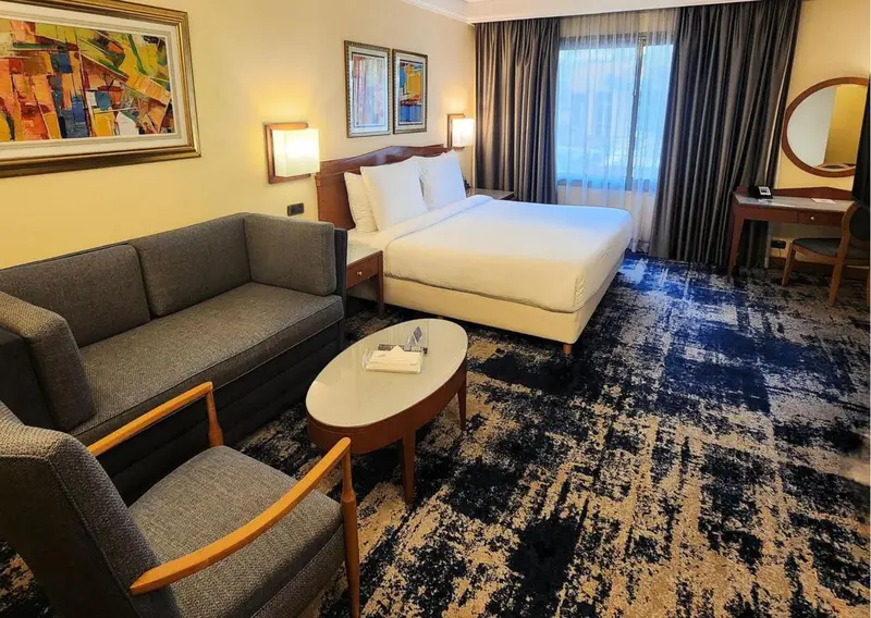Une chambre d'hôtel lumineuse avec un canapé et un bureau.