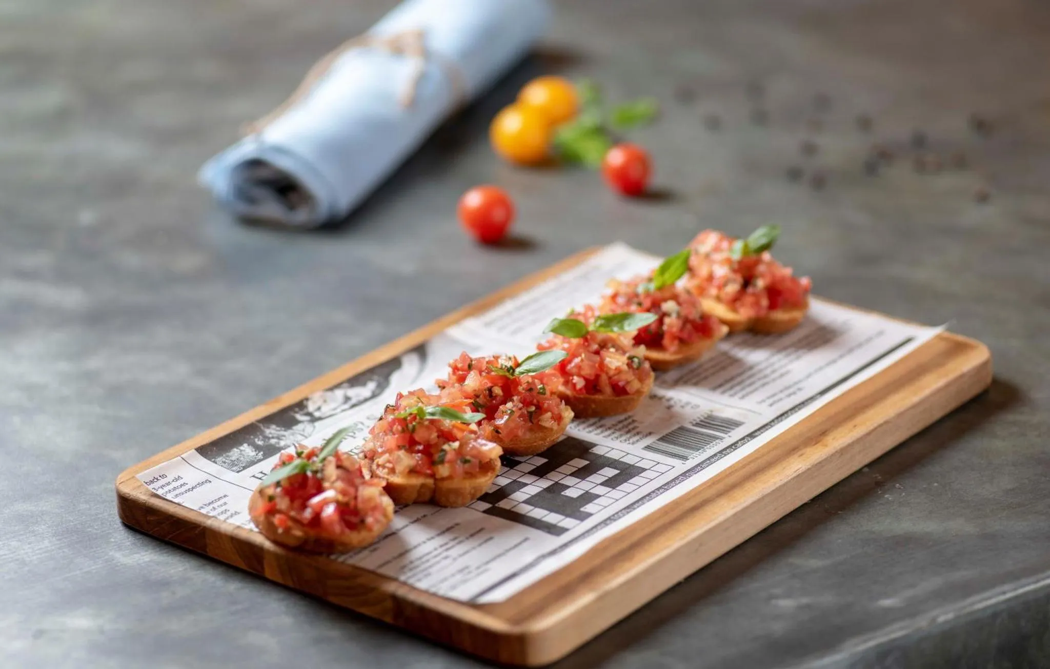 Présentation de petites bouchées à base de tomates et de basilic sur une planche en bois.