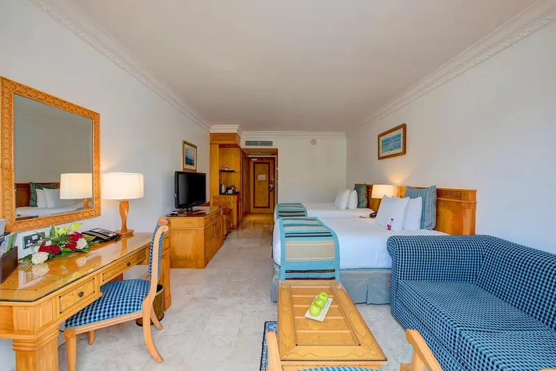 Une chambre lumineuse avec deux lits et un coin salon.