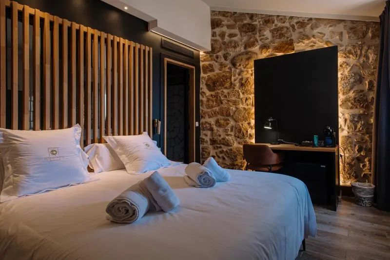 Un lit double est fait dans une chambre aux murs en pierre et en bois.