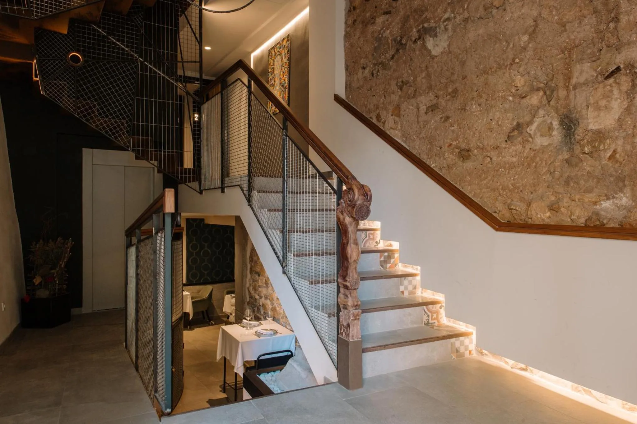 Un escalier en métal et bois mène à un palier éclairé.