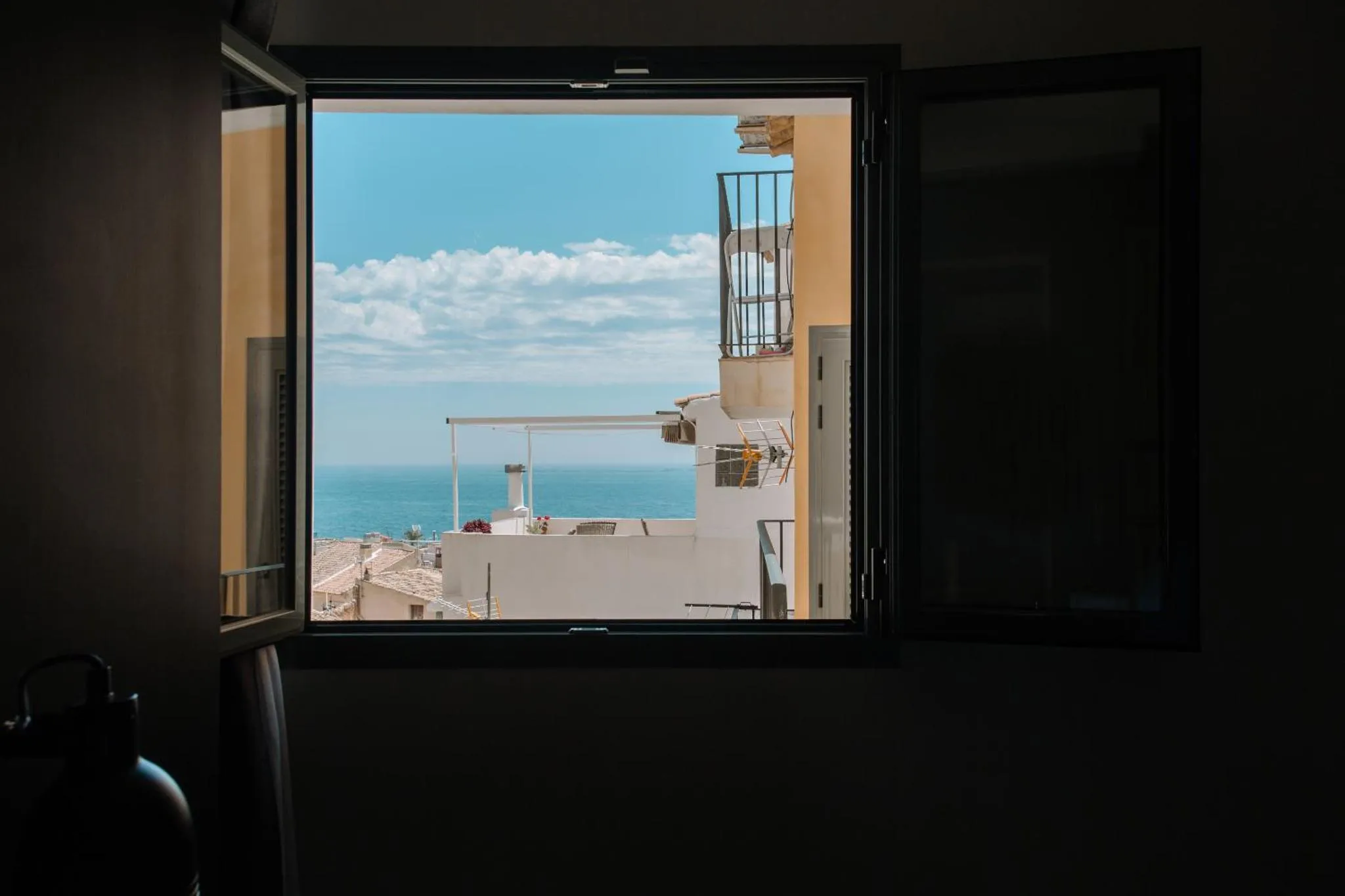 Vue sur la mer depuis une fenêtre ouverte.