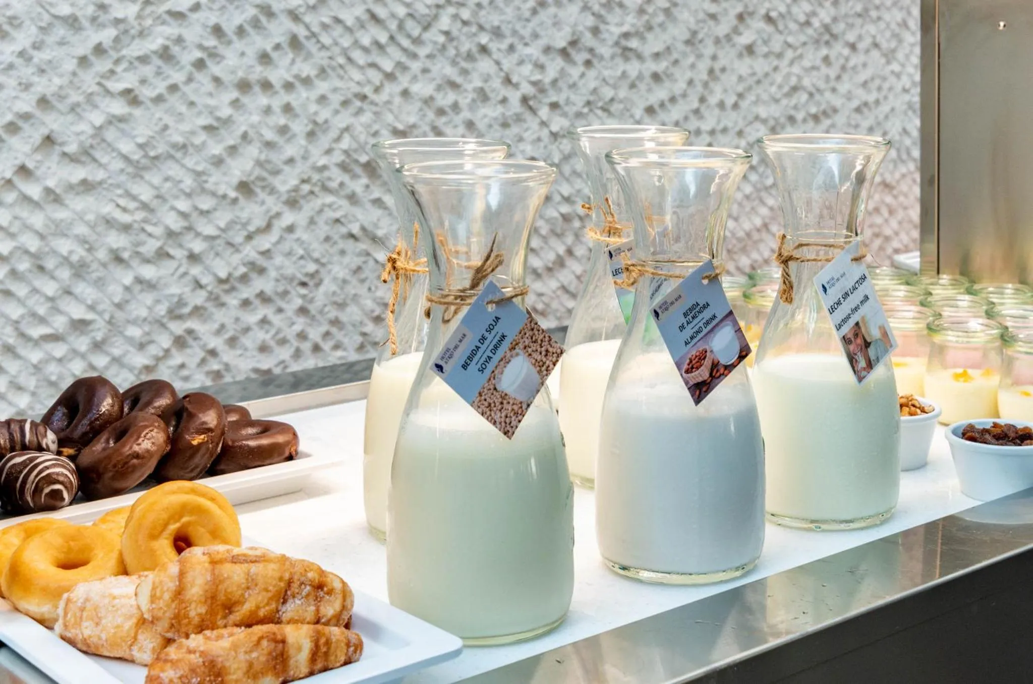 Des carafes de lait végétal et des viennoiseries sont présentées sur un comptoir.