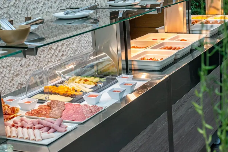 Un buffet propose une selection de charcuteries, fromages et viennoiseries.