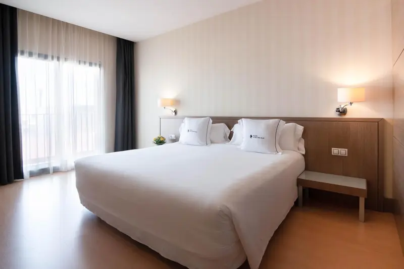 Une chambre lumineuse avec un grand lit recouvert de draps blancs.