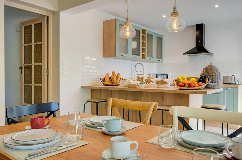 Une table est dressée devant un comptoir de cuisine en bois clair.