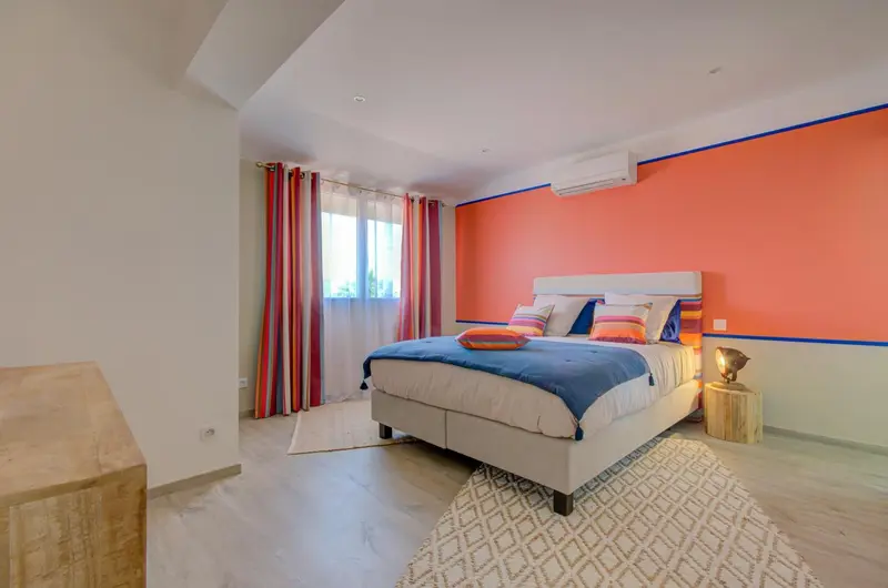 Une chambre lumineuse avec un grand lit et un mur coloré.