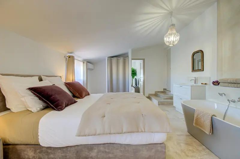 Une chambre lumineuse avec un grand lit et une baignoire.