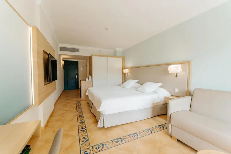 Une chambre lumineuse avec un grand lit et un coin salon.