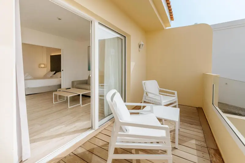 Terrasse aménagée avec mobilier blanc donnant sur une pièce lumineuse.