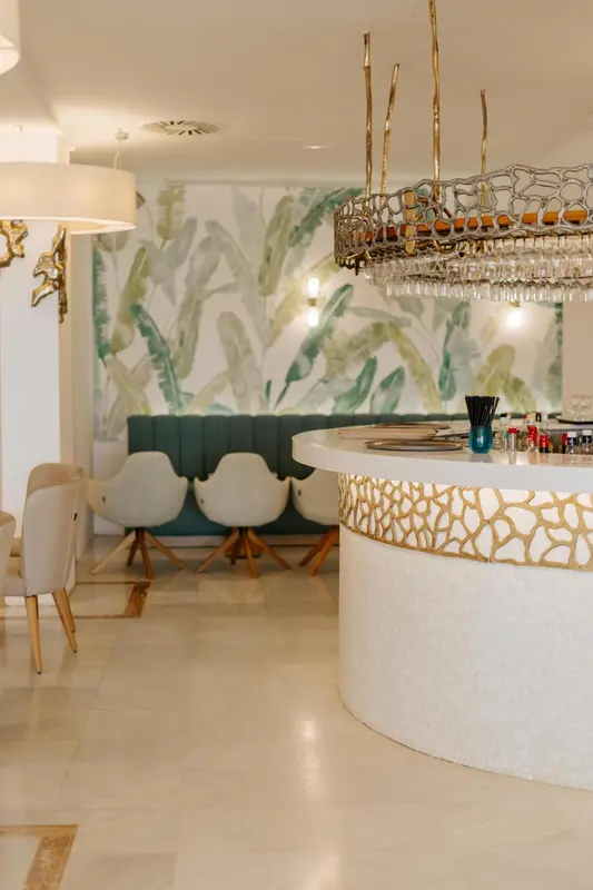 Un bar lumineux avec un comptoir incurvé et des sièges blancs.