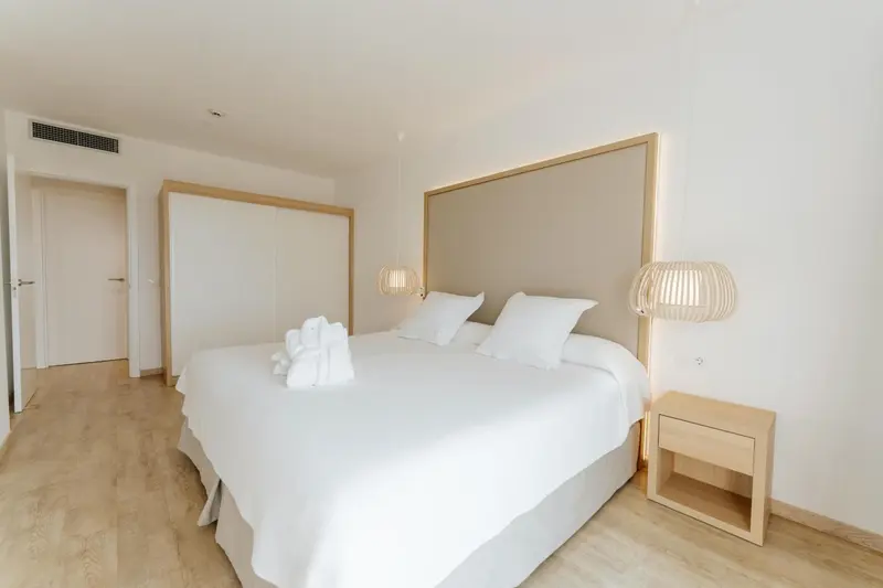 Une chambre lumineuse avec un grand lit recouvert de draps blancs.