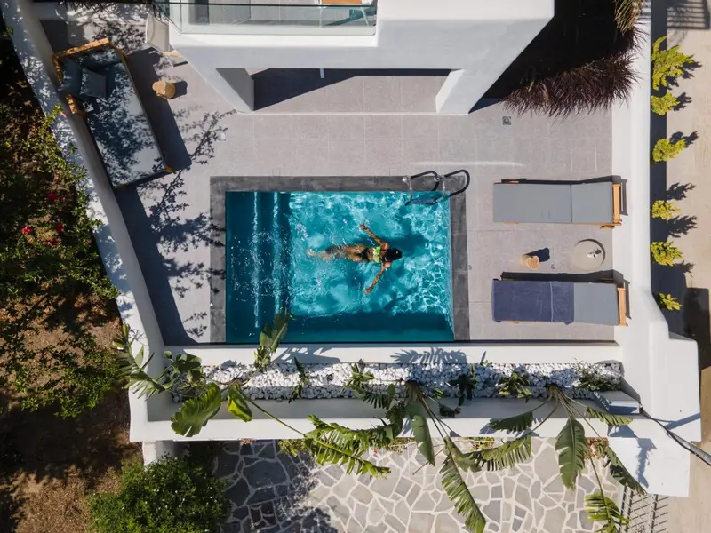 Vue aérienne d'une piscine rectangulaire entourée d'une terrasse aménagée.