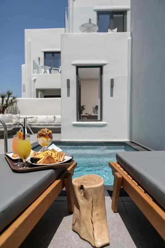 Un plateau de nourriture et de boissons est servi sur des transats au bord d'une piscine.