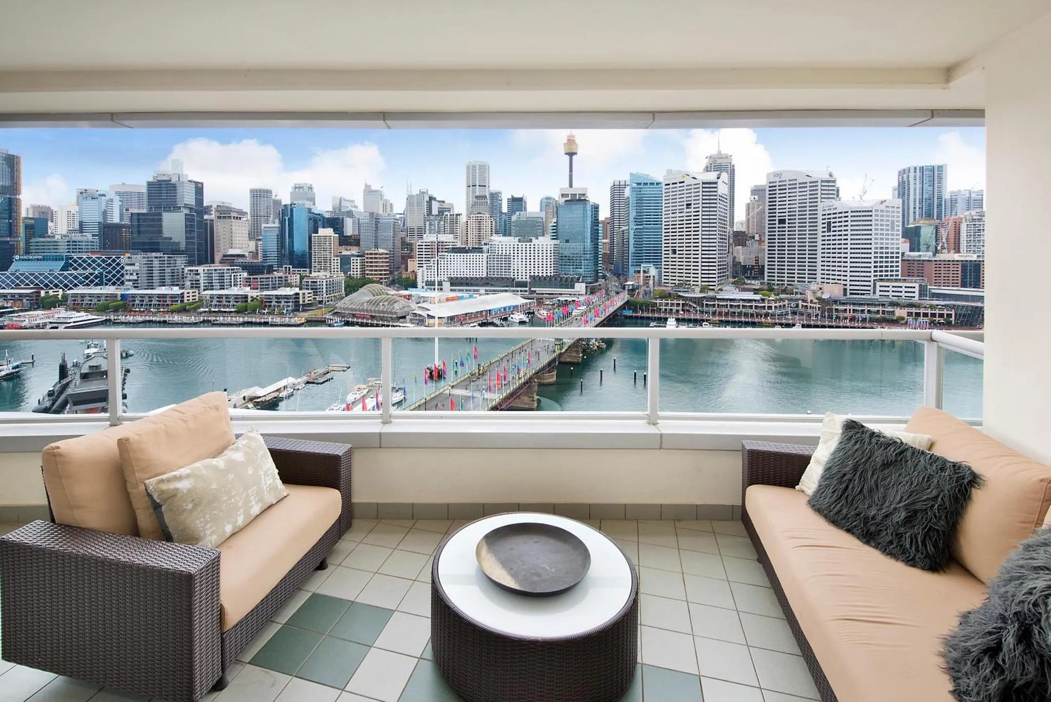 Terrasse aménagée avec canapés et vue sur une ville portuaire.