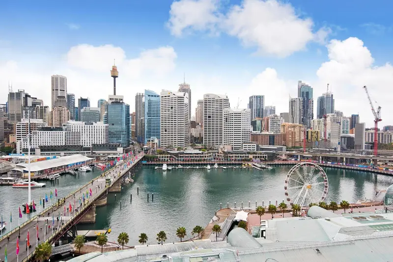 Vue panoramique sur un port de ville avec des gratte-ciel et une grande roue.