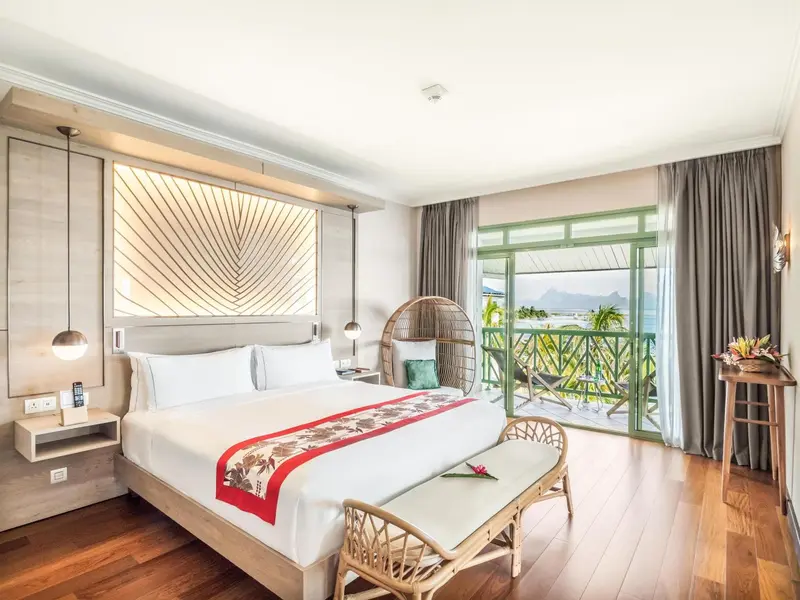 Chambre lumineuse avec un grand lit et une vue sur la mer.