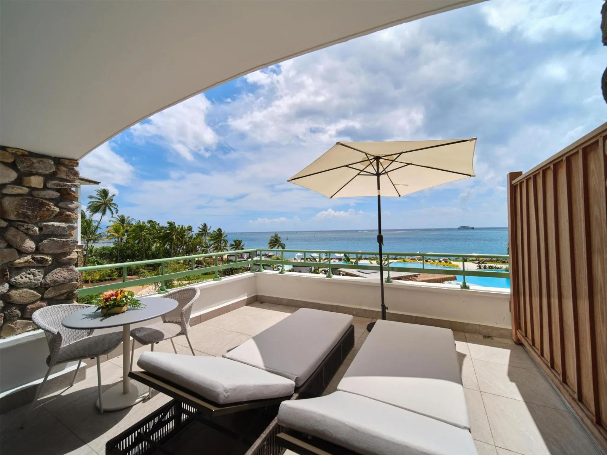 Terrasse aménagée avec salon de jardin et transats donnant sur la mer.