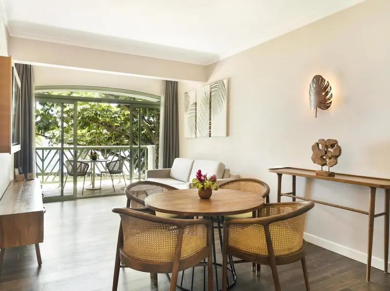 Espace de vie lumineux avec coin repas et accès à un balcon.