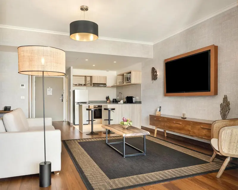 Espace de vie lumineux avec canapé, table basse et cuisine équipée.