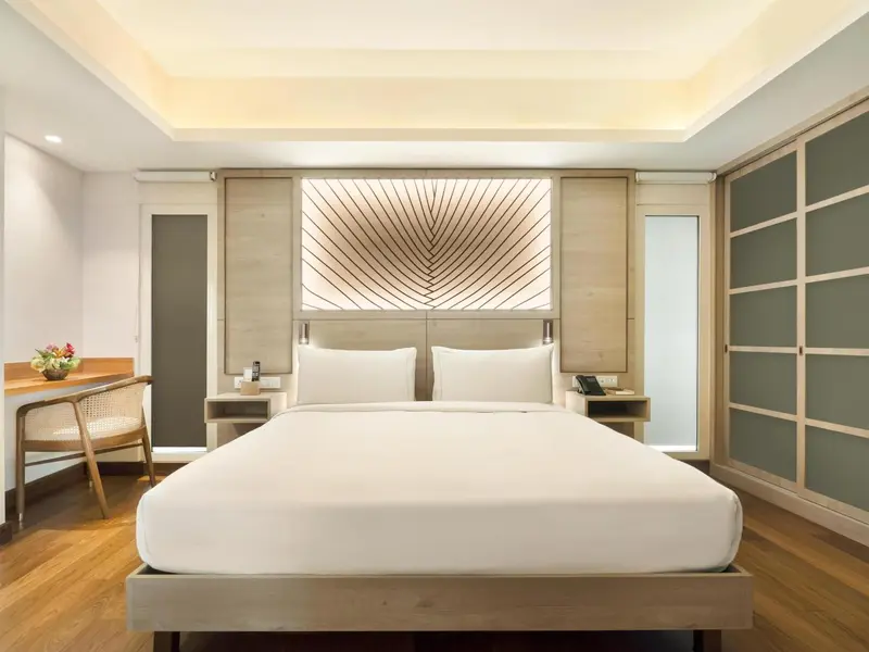 Une chambre lumineuse avec un grand lit et un bureau en bois.