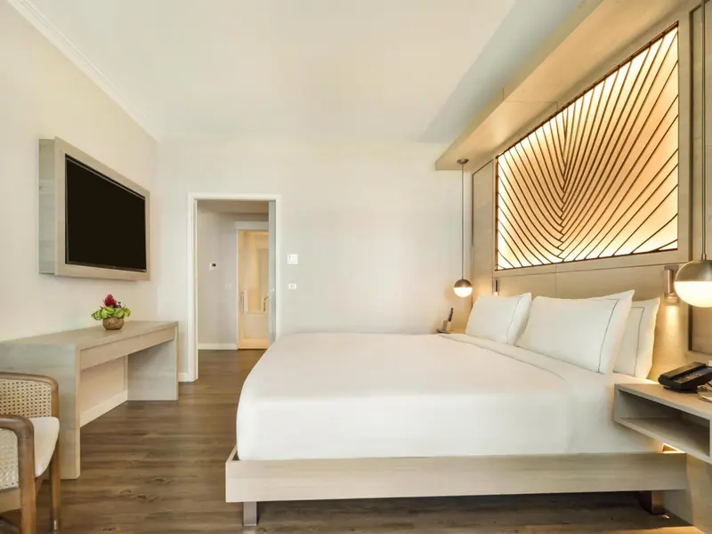 Une chambre lumineuse avec un grand lit et un bureau.