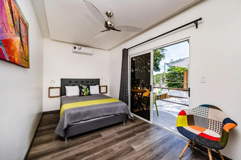 Une chambre lumineuse avec un lit double et un accès à une terrasse.