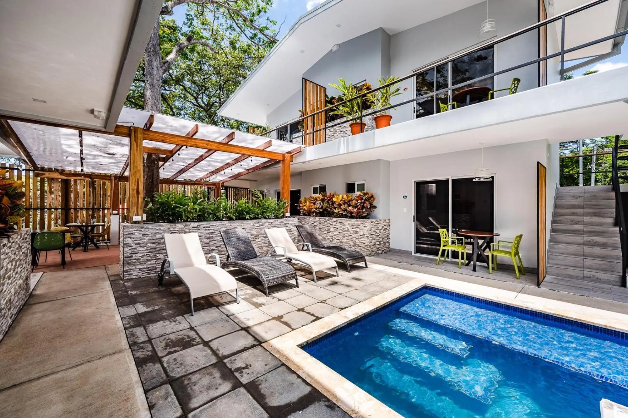 Espace extérieur avec piscine, chaises longues et pergola ombragée.