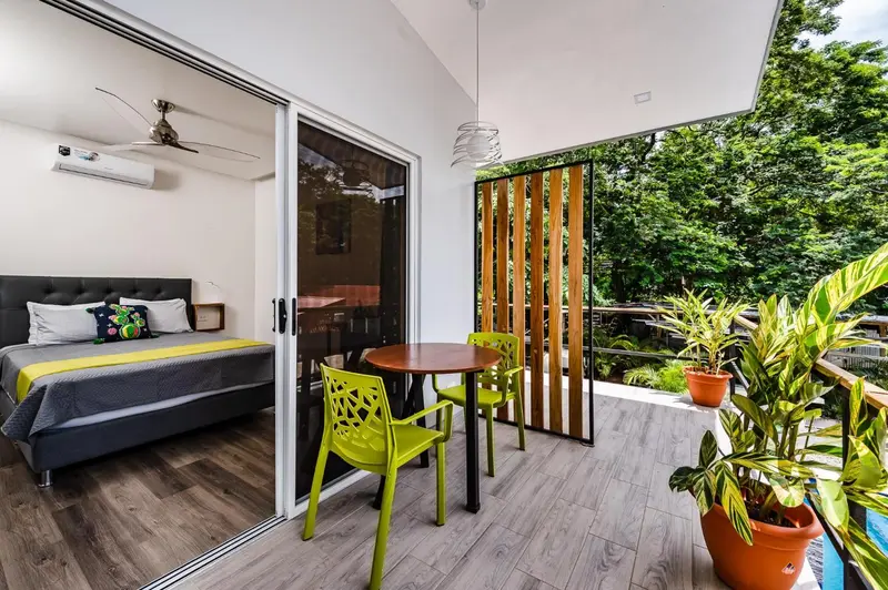 Une chambre lumineuse s'ouvre sur une terrasse avec table et chaises.