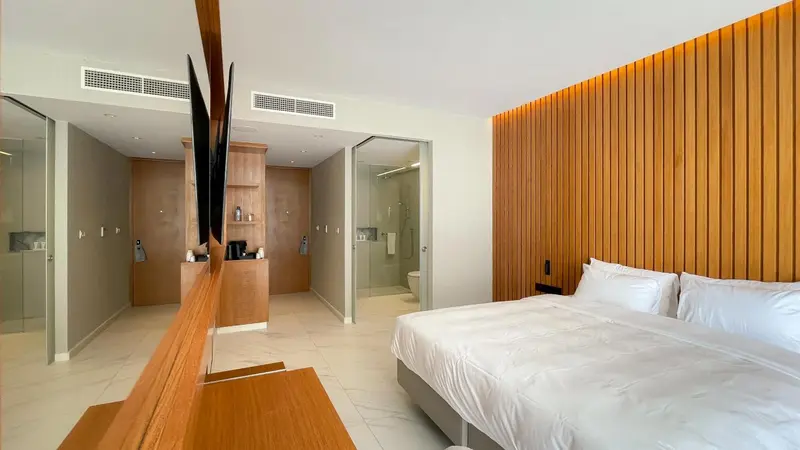 Une chambre lumineuse avec un grand lit et un accès à une salle de bain.