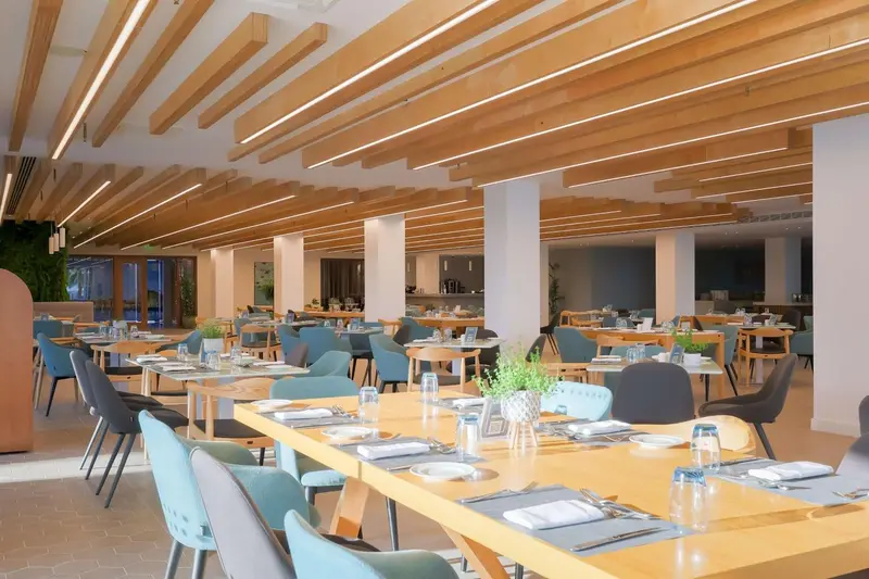 Une salle lumineuse avec des tables dressées pour un repas.
